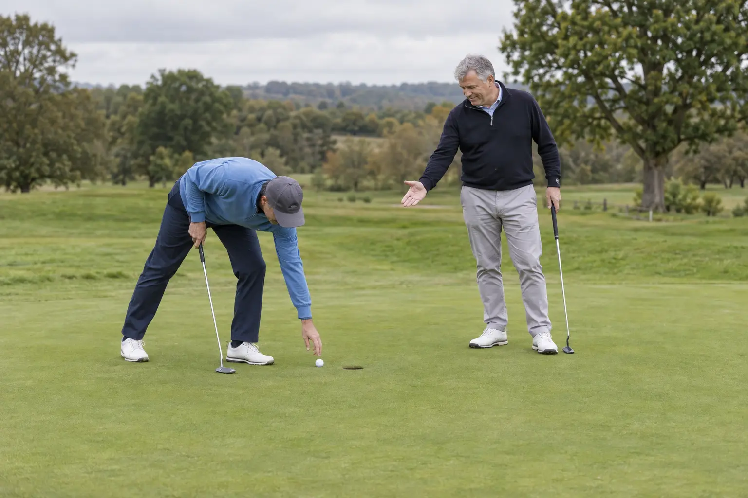 Two golfers on a putting green as a short putt is conceded in match play